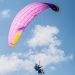 Experience the thrill of tandem paragliding with colorful parachute soaring high in the clear blue sky.